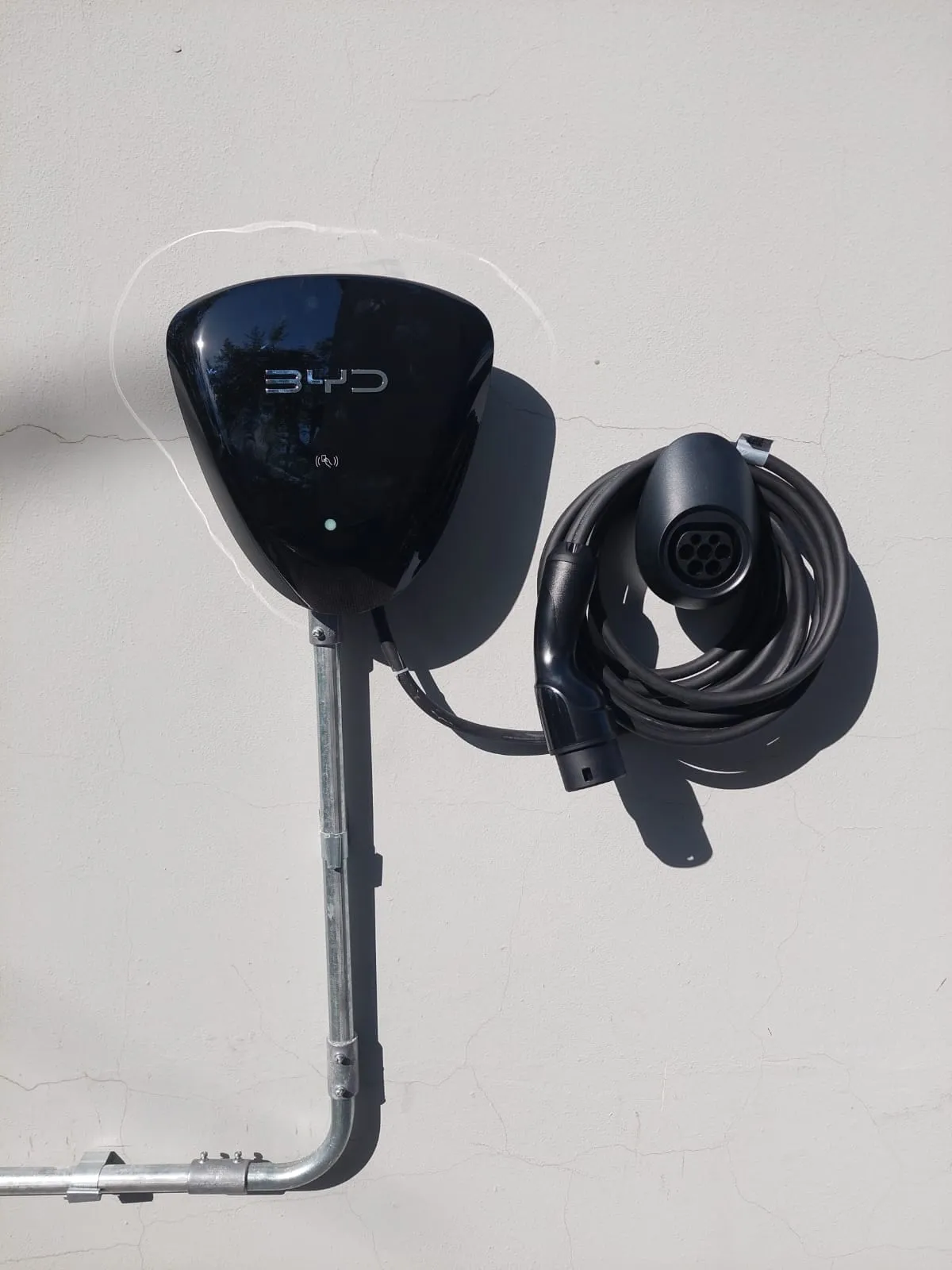 Cargador de auto eléctrico en pared exterior, alimentado por cañería metálica galvanizada